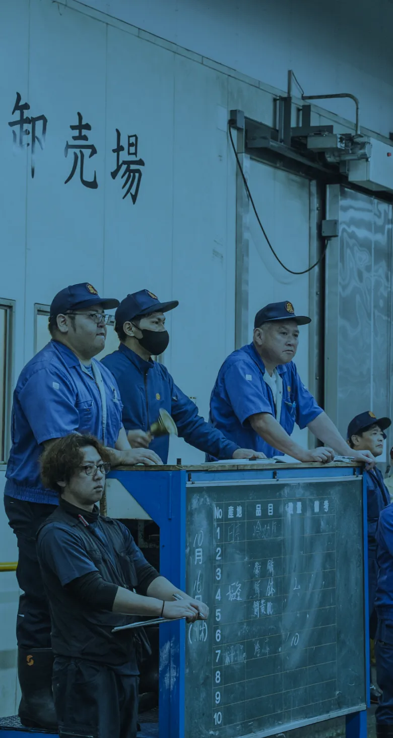 市場で競りを見守るスタッフ